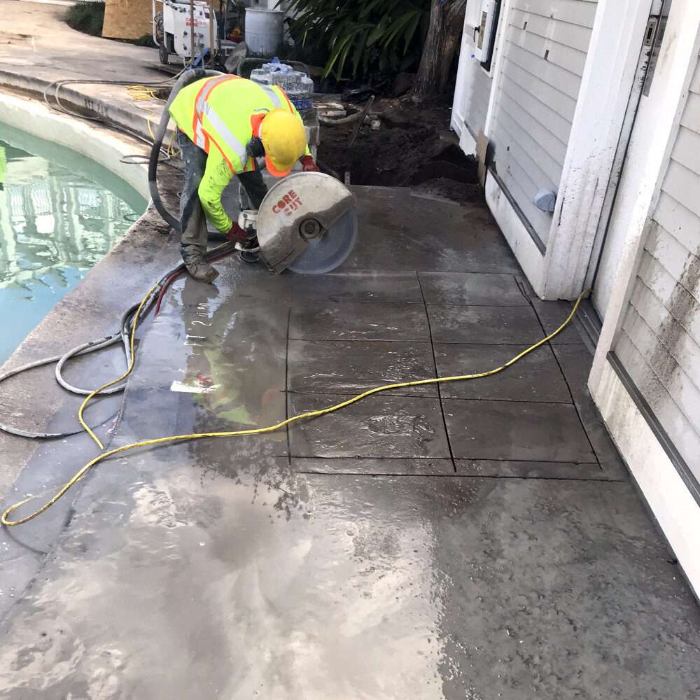 worker using handheld concrete saw for precision cutting near pool area