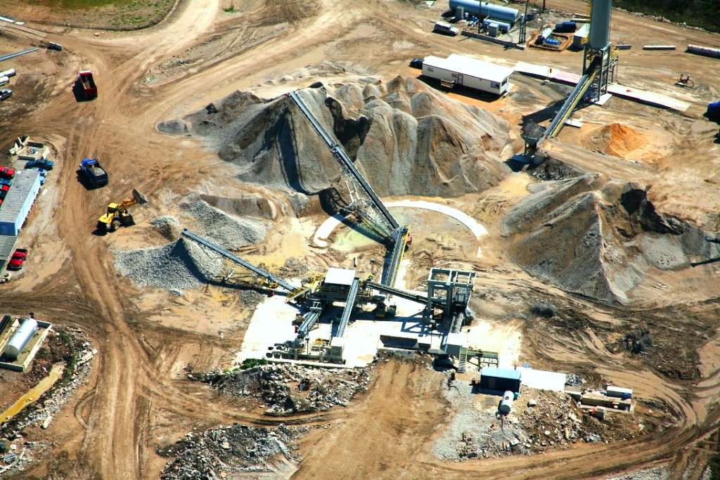 Aerial view of a concrete recycling plant with conveyor belts and piles of aggregate material
